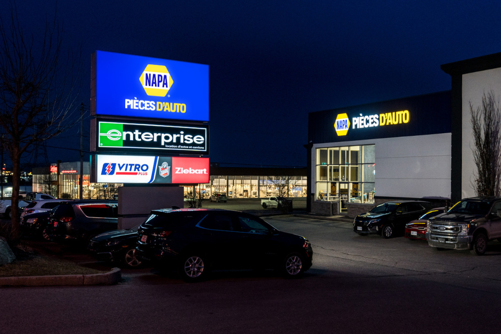 Photo de soir vue en perspective de l'enseigne détachée et de l'enseigne murale